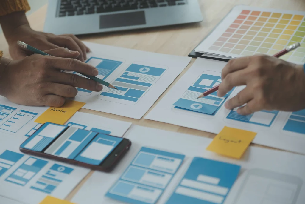 UX designers and developers reviewing mobile app wireframes and user engagement analytics to improve customer retention and business growth.